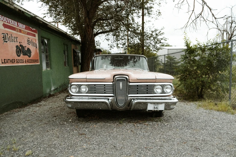 old pink car parked in gravel near building