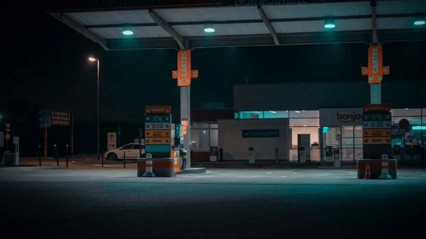 an empty gas station at night with green lights