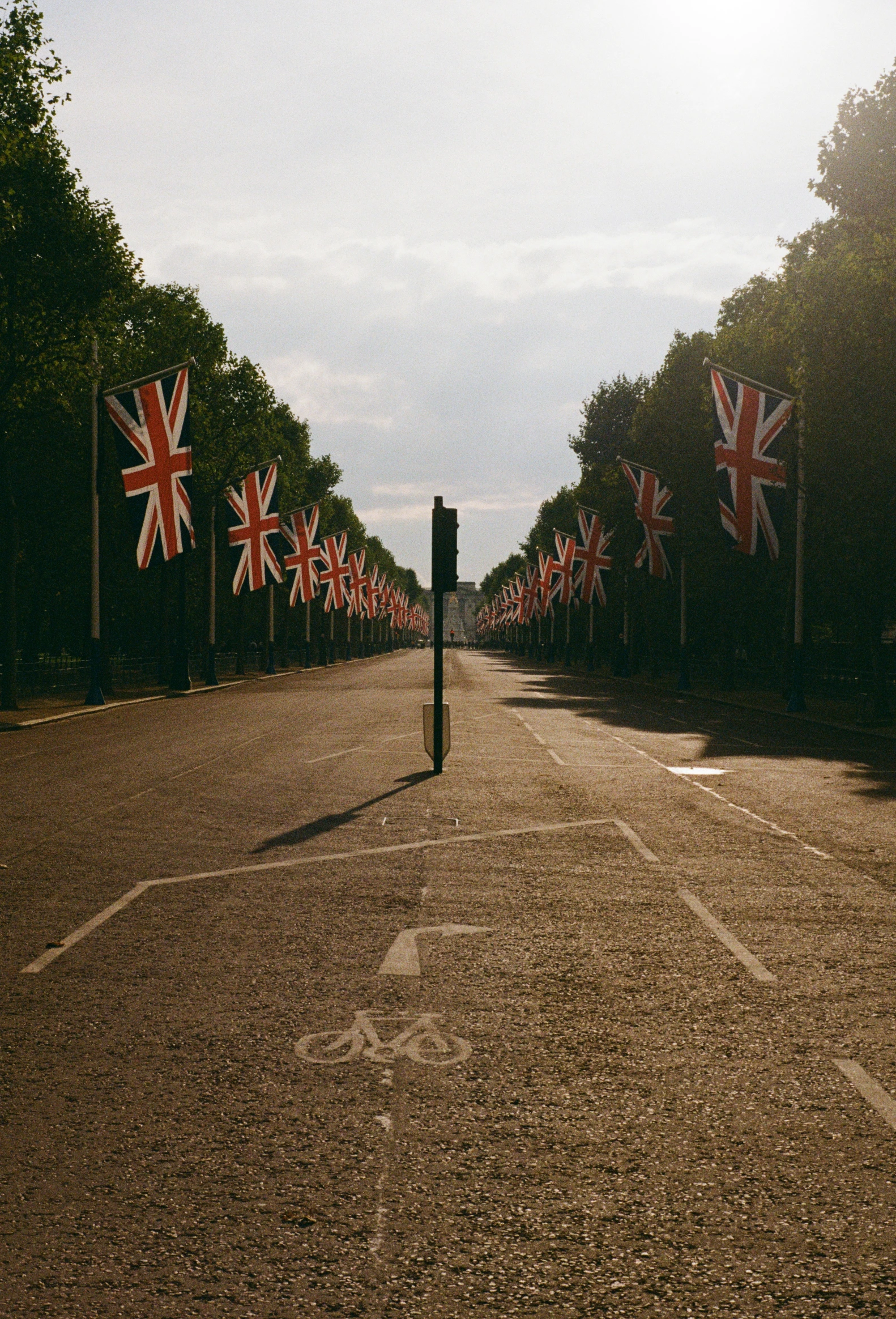 there are a lot of british flags hanging on a tree lined street