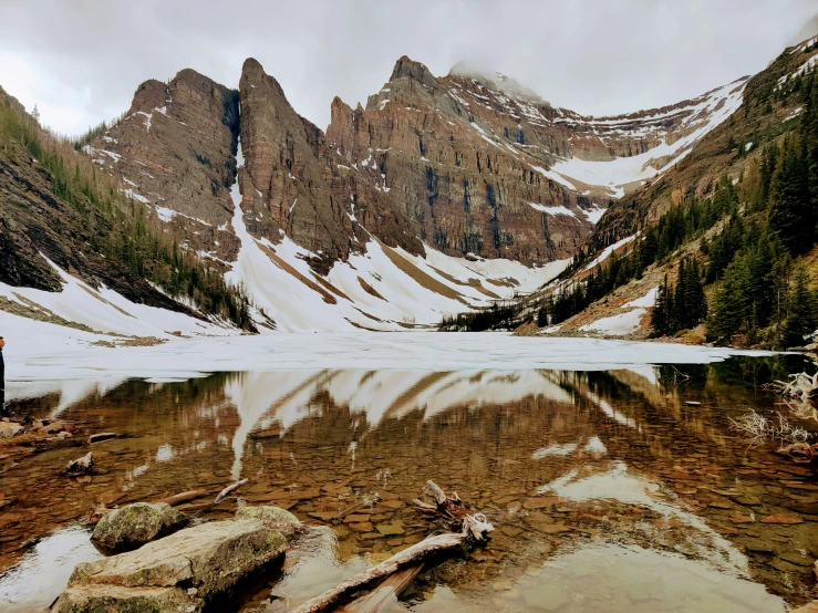 a person is standing on a mountain top looking at a lake