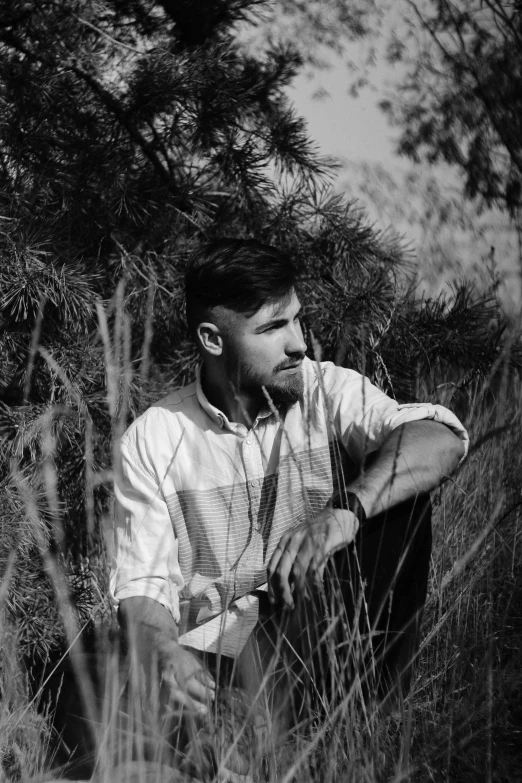 a man wearing earphones and sitting in some tall grass