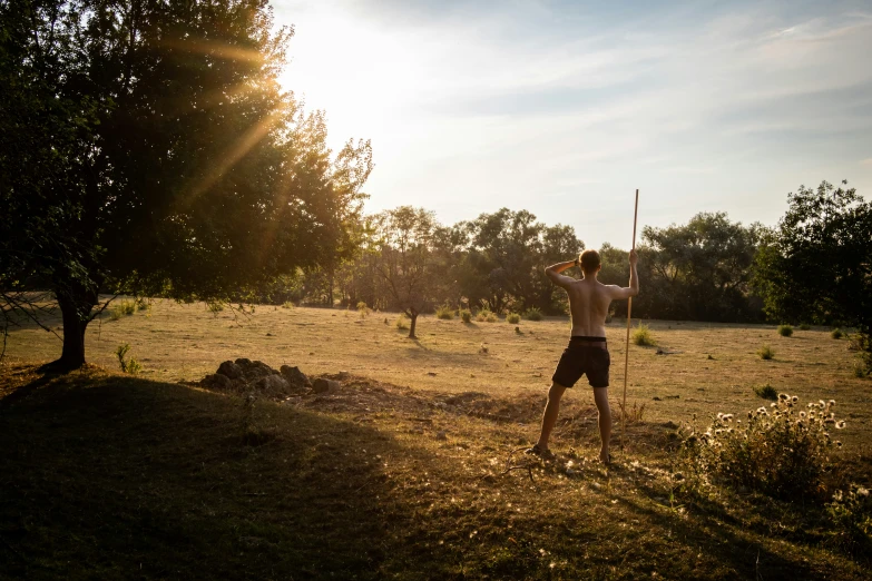 a man is standing in the sun and holding an object