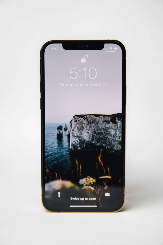 a phone with the image of the sea and rocks in it