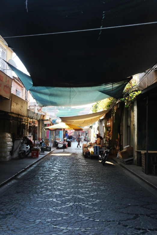 a street in an asian town with tables covered by tarps