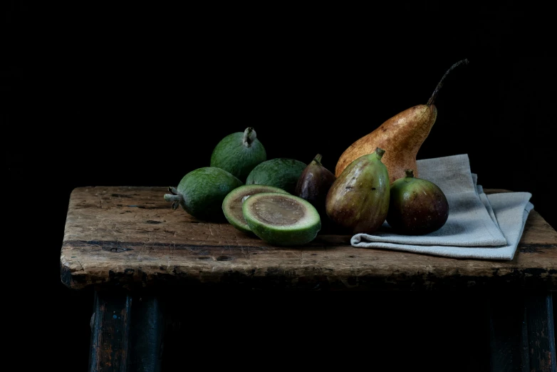 a still life pograph of some pears, avocados and a brown pear on top of a table