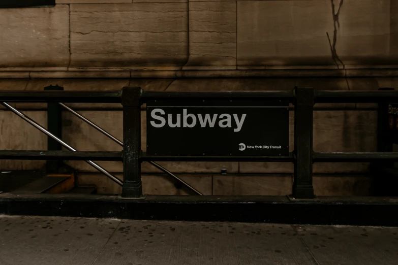 subway sign near subway stop in city street at night