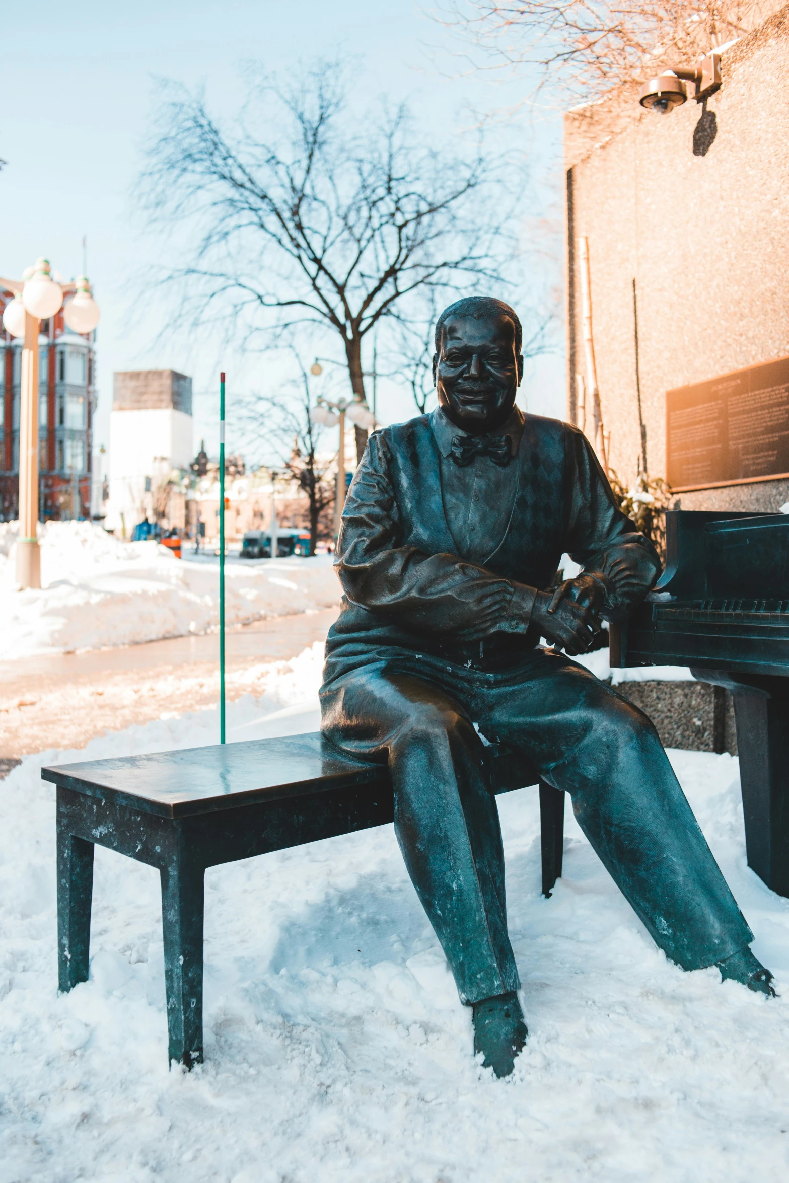 a statue of a man sitting on a bench next to a piano