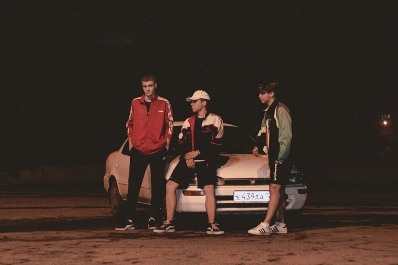 a group of young men standing by a sports car