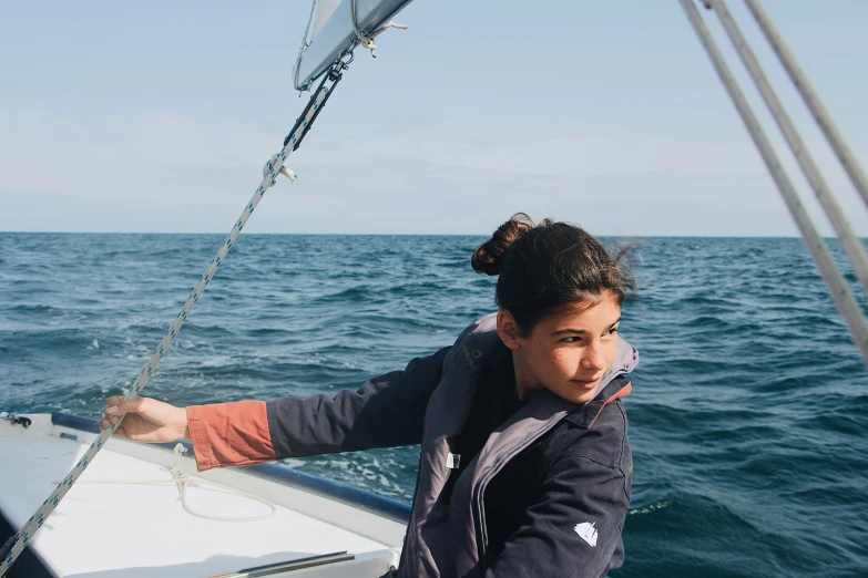 there is a young lady sitting on the bow of a sailboat