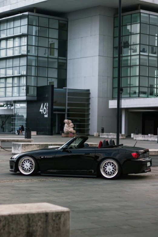 a black bmw convertible parked outside a tall glass building