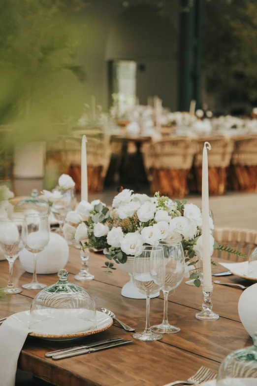 a wooden table topped with white flowers and lit candles