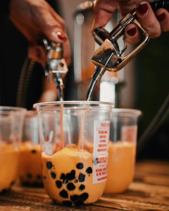 two hands fill s glasses with orange liquid