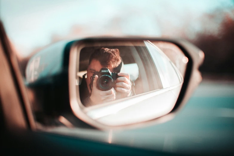 a man is taking a po in the side mirror of a car