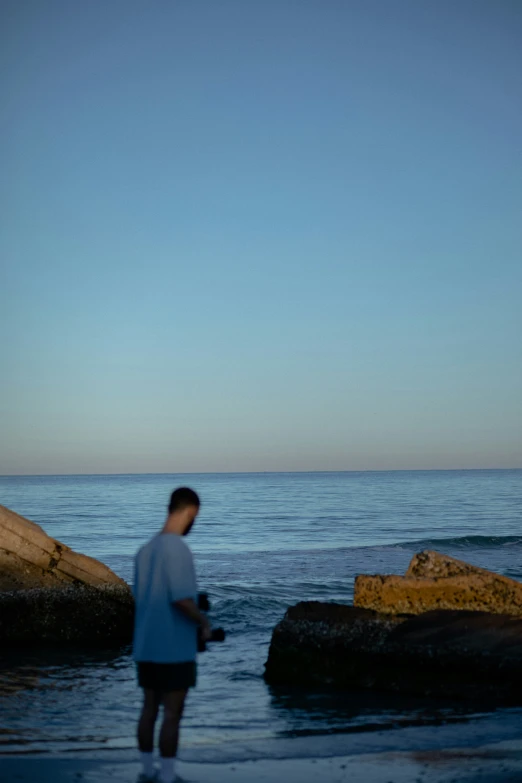 a person is standing on rocks looking out to the ocean