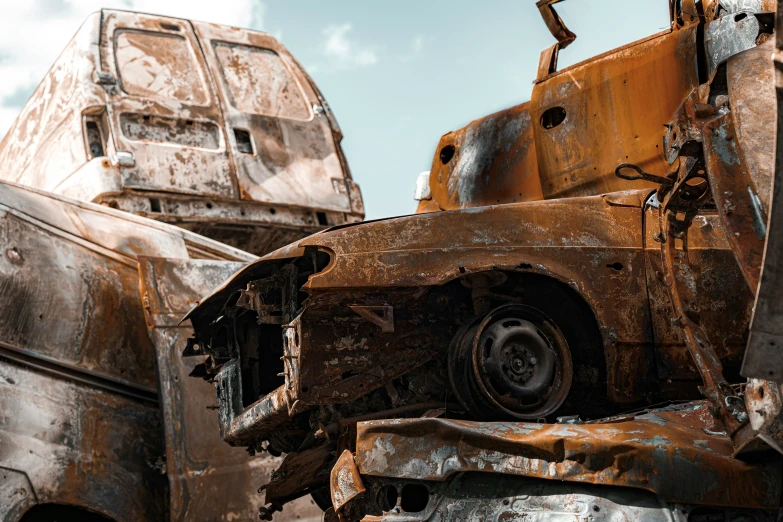 rusted cars sit in the junk yard