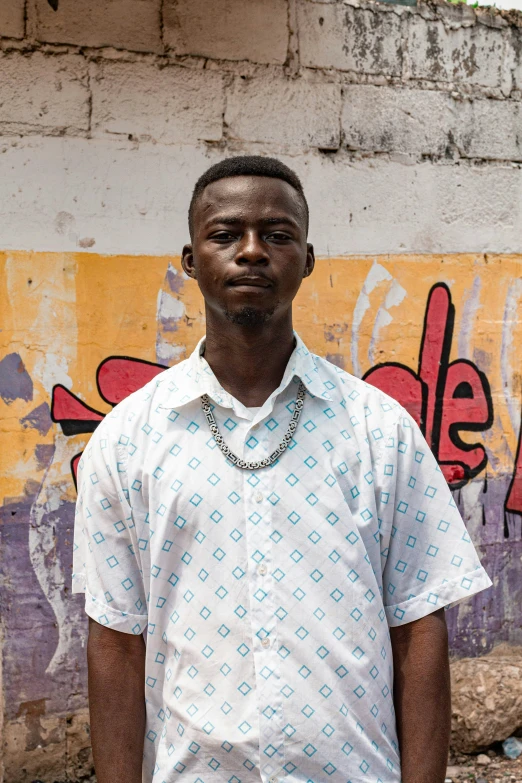 a man wearing a white shirt stands in front of graffiti