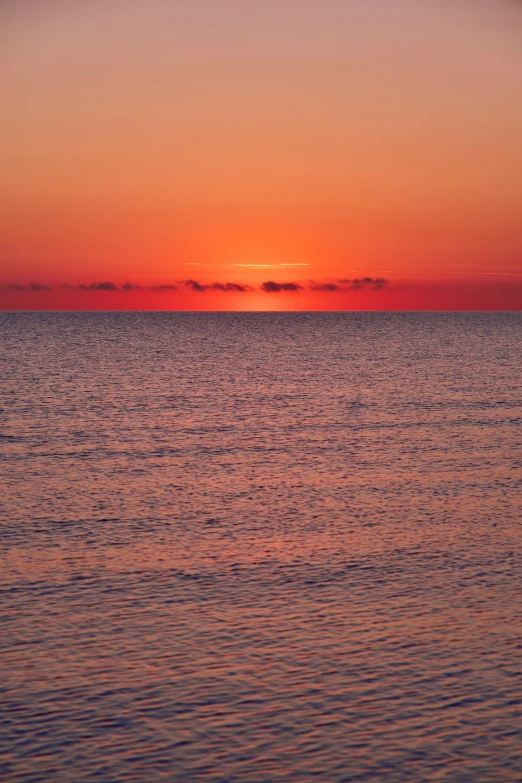 the setting sun rises behind the horizon of water