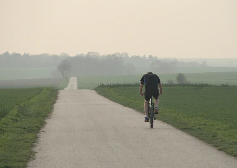 a person riding a bicycle on a long country road