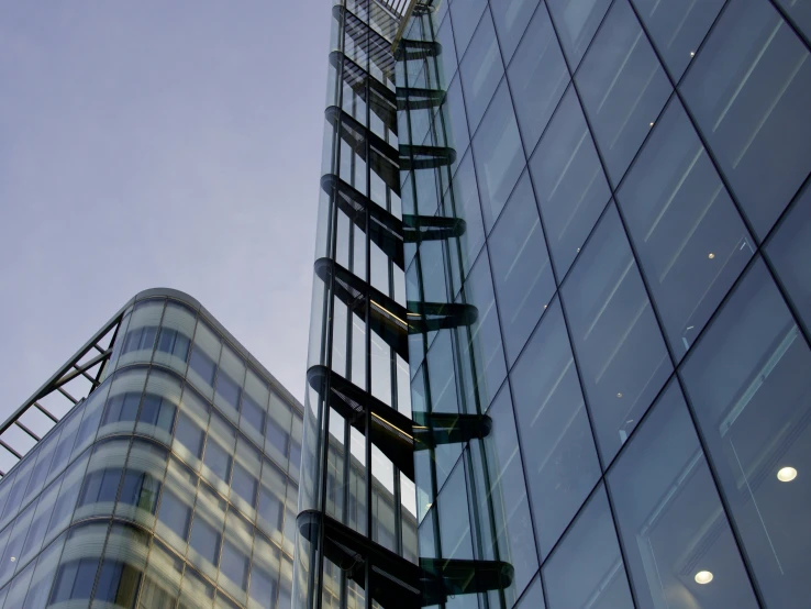 large glass building next to a skyscr on a cloudy day