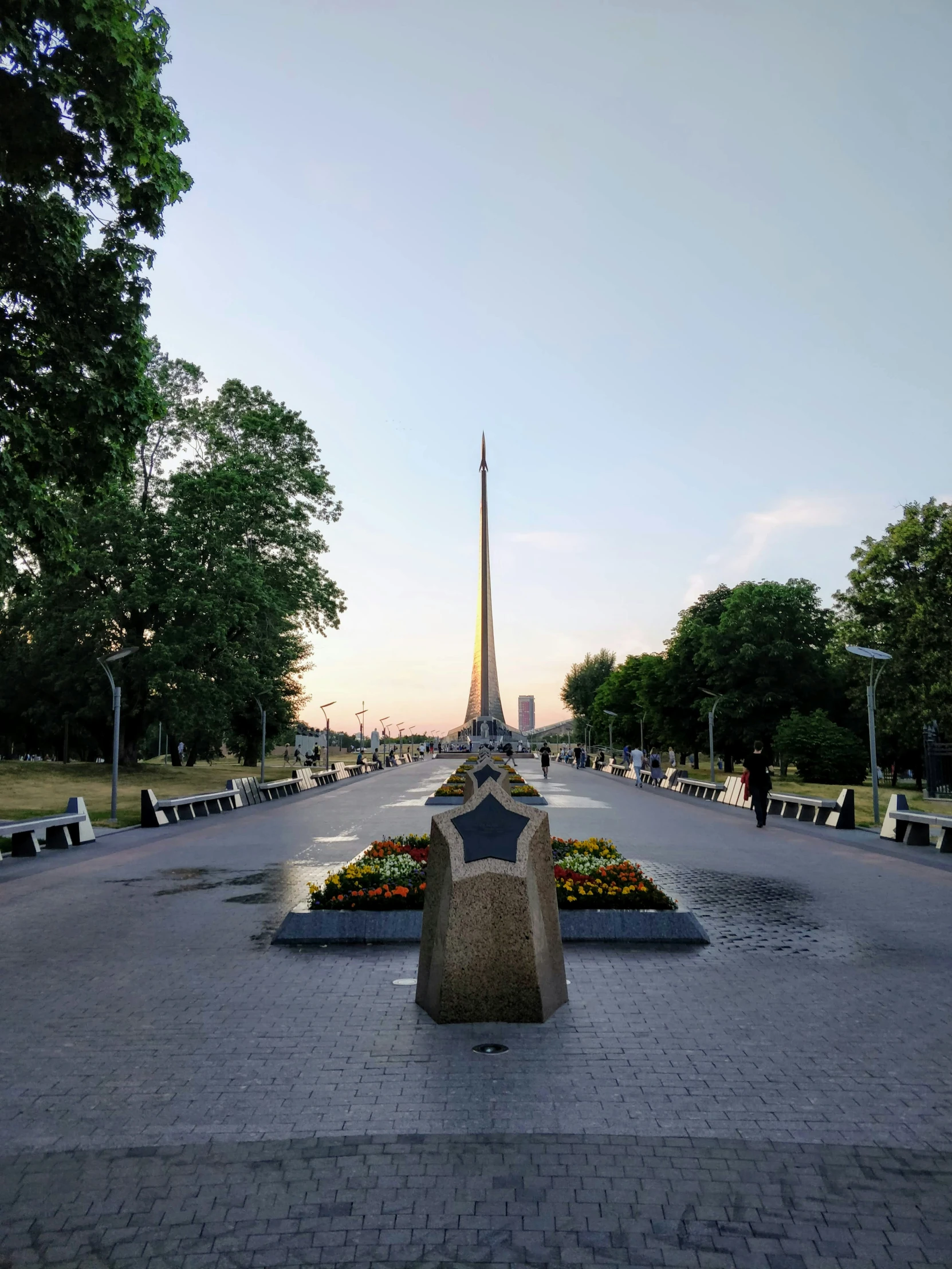 a wide street with flowers and statues near by