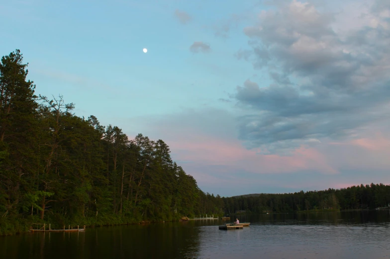 boat on a lake surrounded by trees at sunset