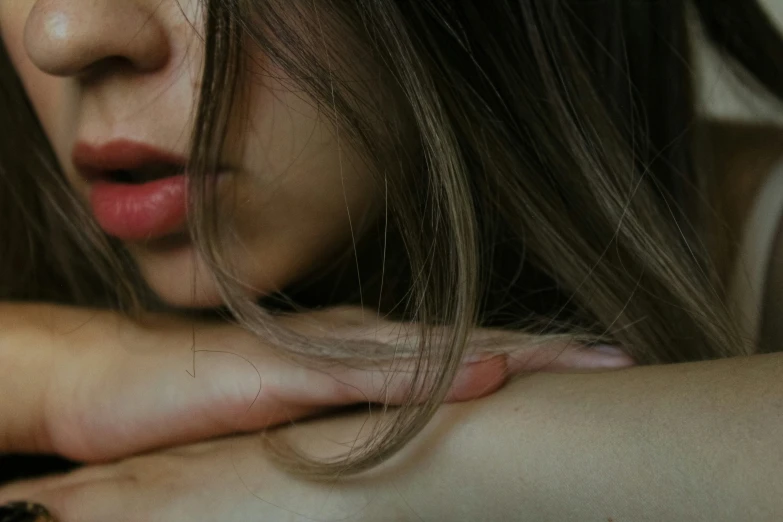 a woman with long hair and blue eyes staring behind her arm