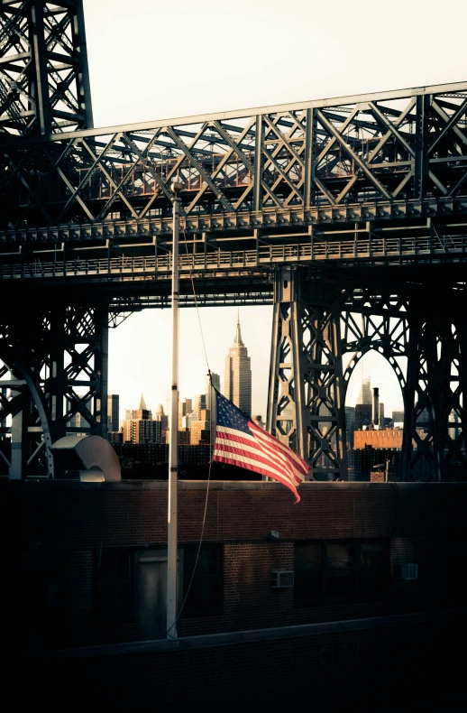 an american flag flies in front of a steel bridge