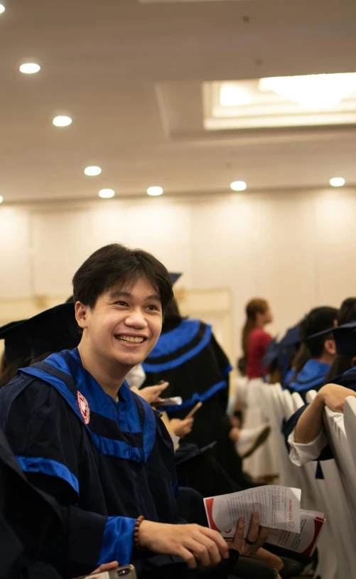 man in blue graduation dress holding a piece of paper