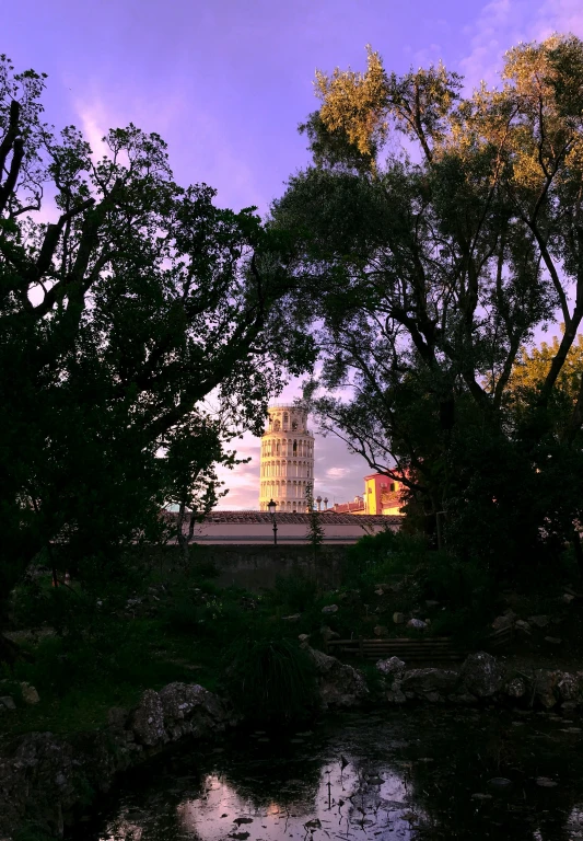 a tower in the distance with some trees and a body of water below