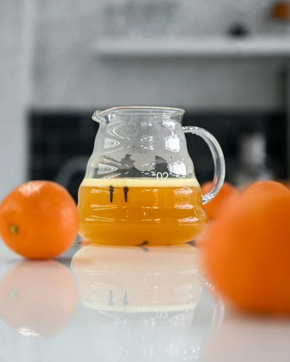 a pitcher with some liquid and oranges on a table