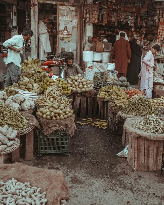an outdoor vegetable market with various vegetables and people