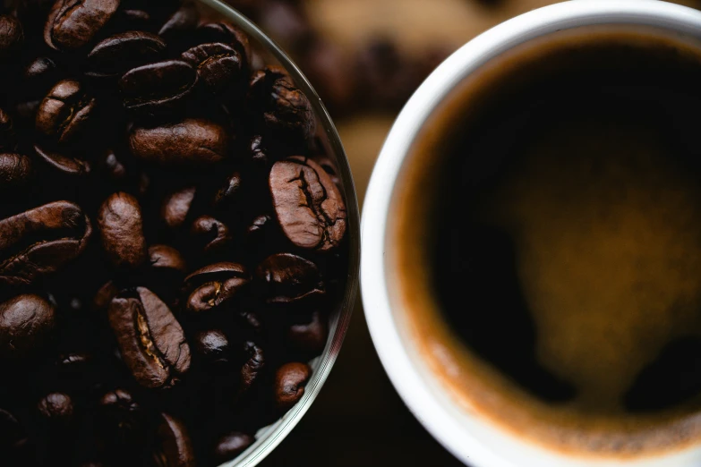 a coffee cup and a white bowl with some coffee beans on it