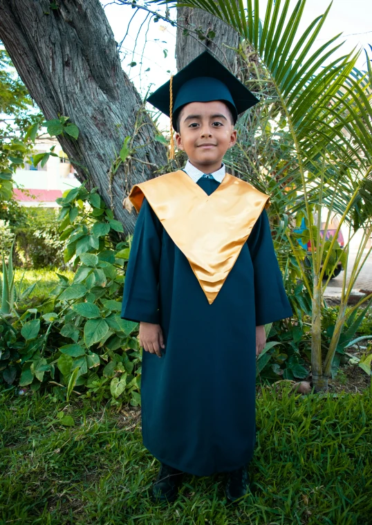 boy wearing graduation gown and cap in the yard