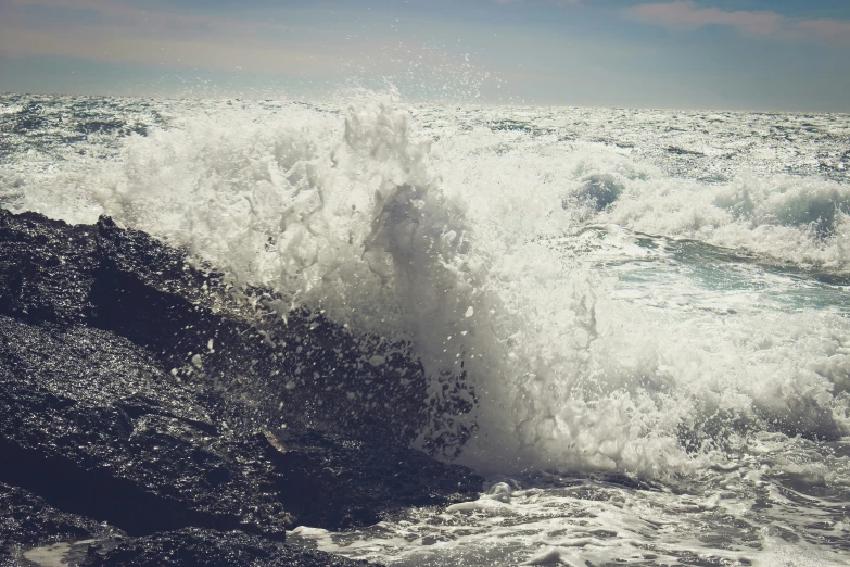 large ocean wave crashing onto the rocky shore