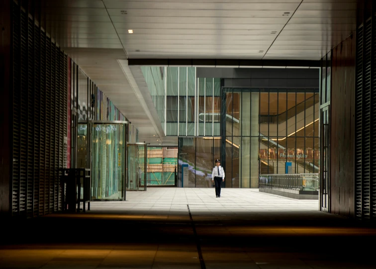 a man walks away from the entrance of a glass - walled building