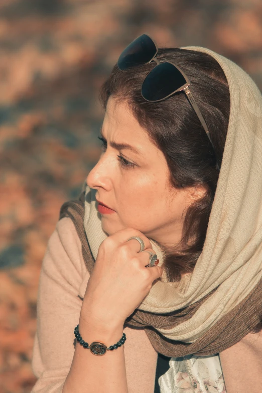 a woman with sunglasses and a scarf standing in a field