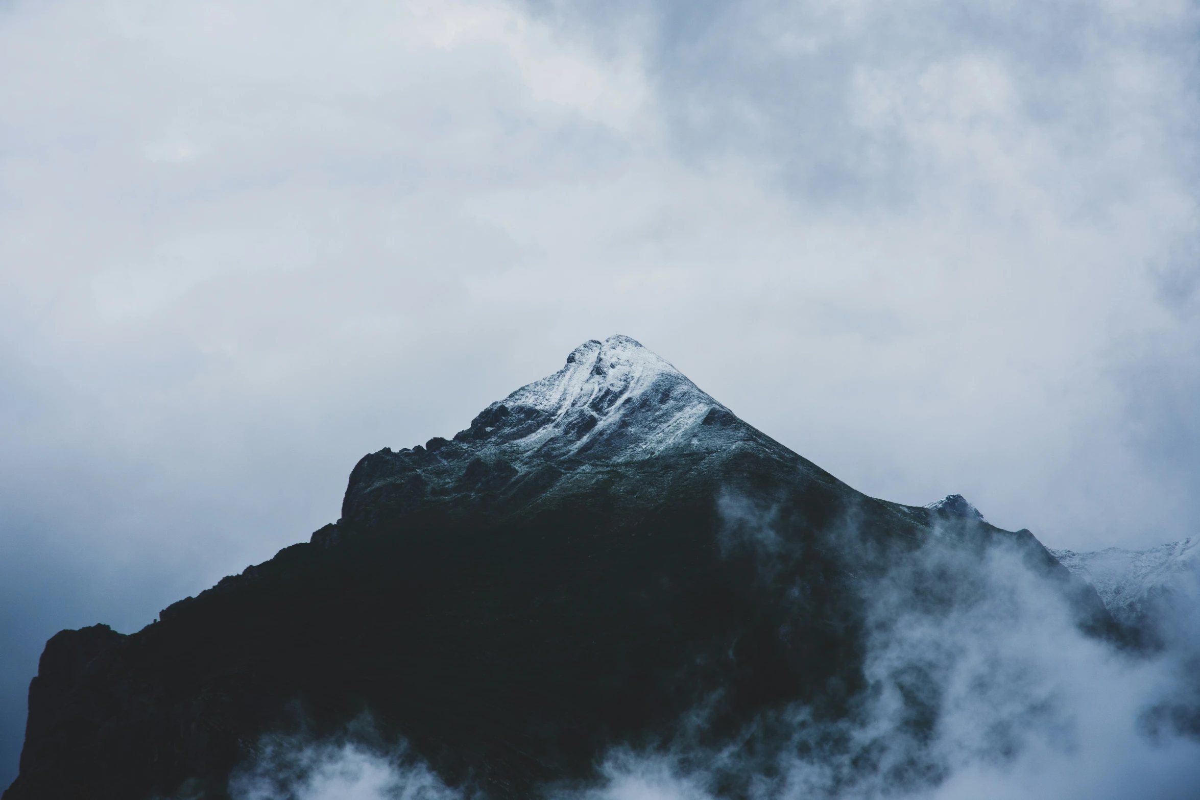 the top of the mountain is seen through clouds