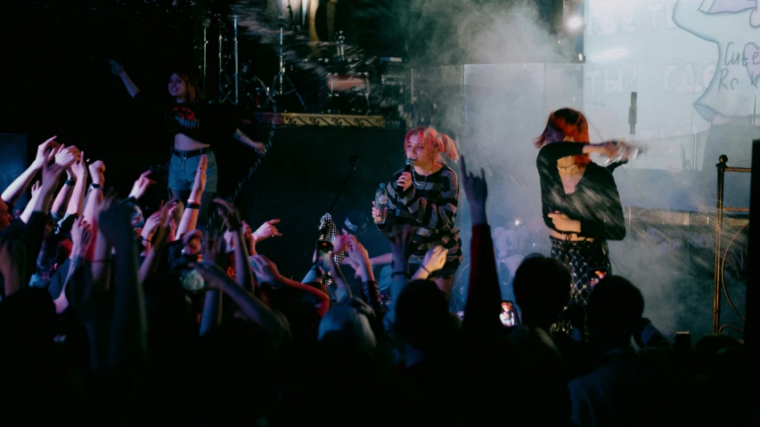 two woman in concert one with red hair and one with blond hair, one holding hands out