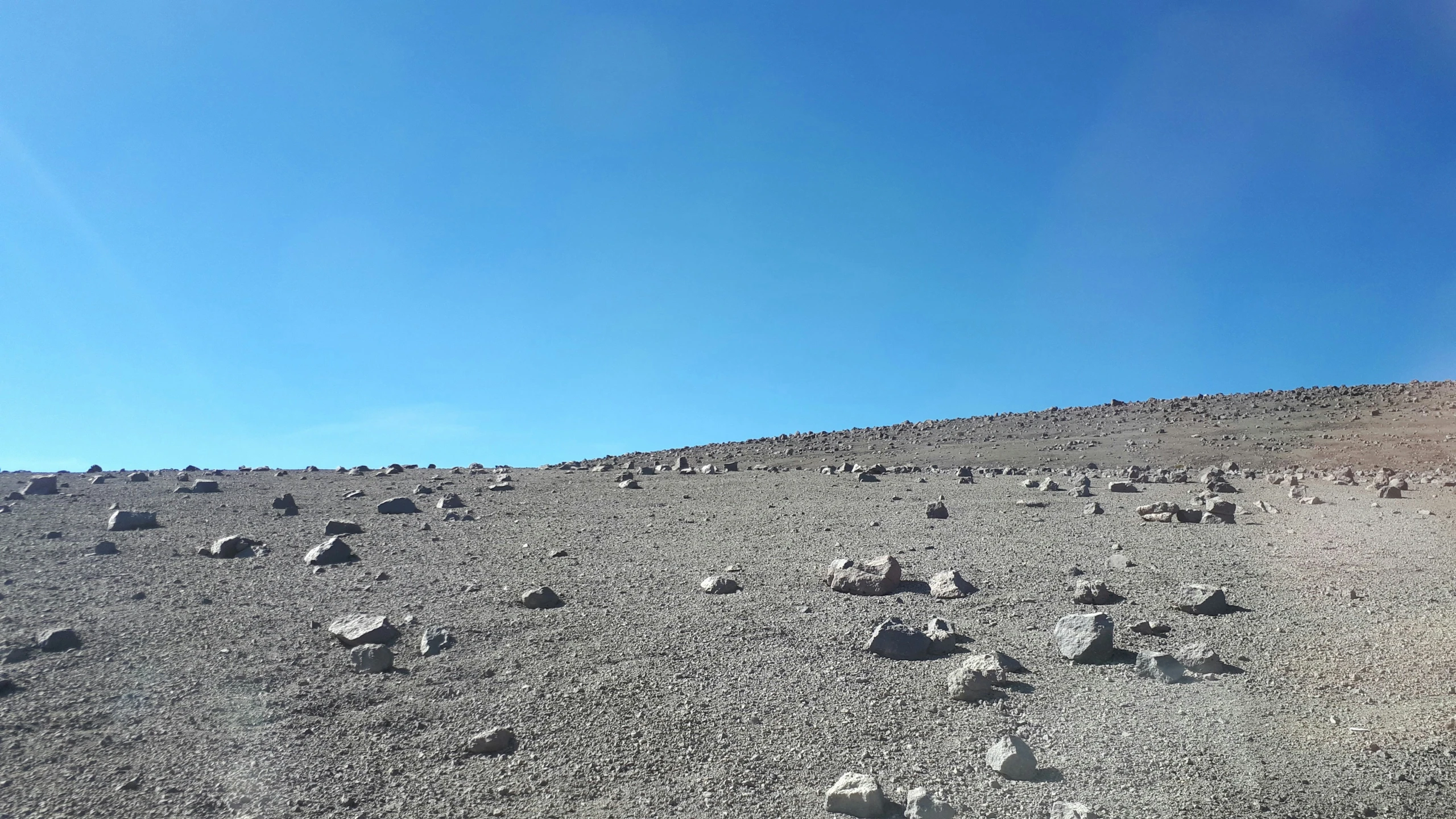 a rock hillside with a bright blue sky in the background