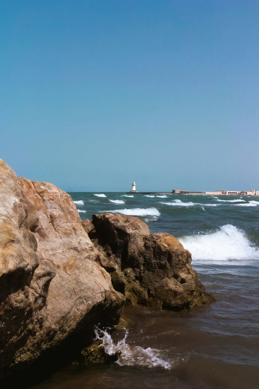 a person sits on the rocks in front of the ocean