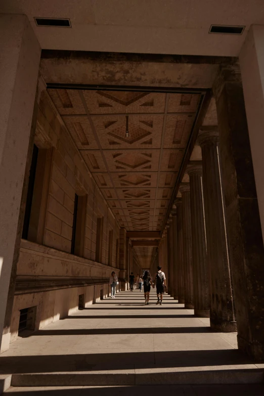 a hallway with several columns and people walking down one