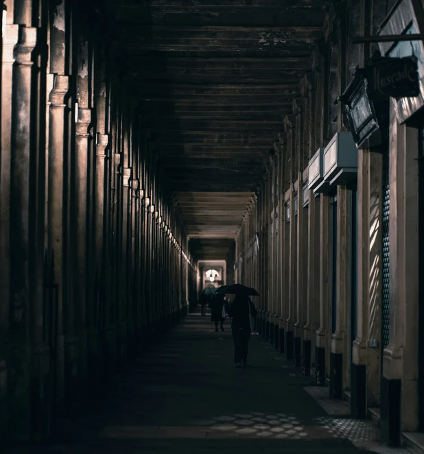 several people with umbrellas walking down a hallway