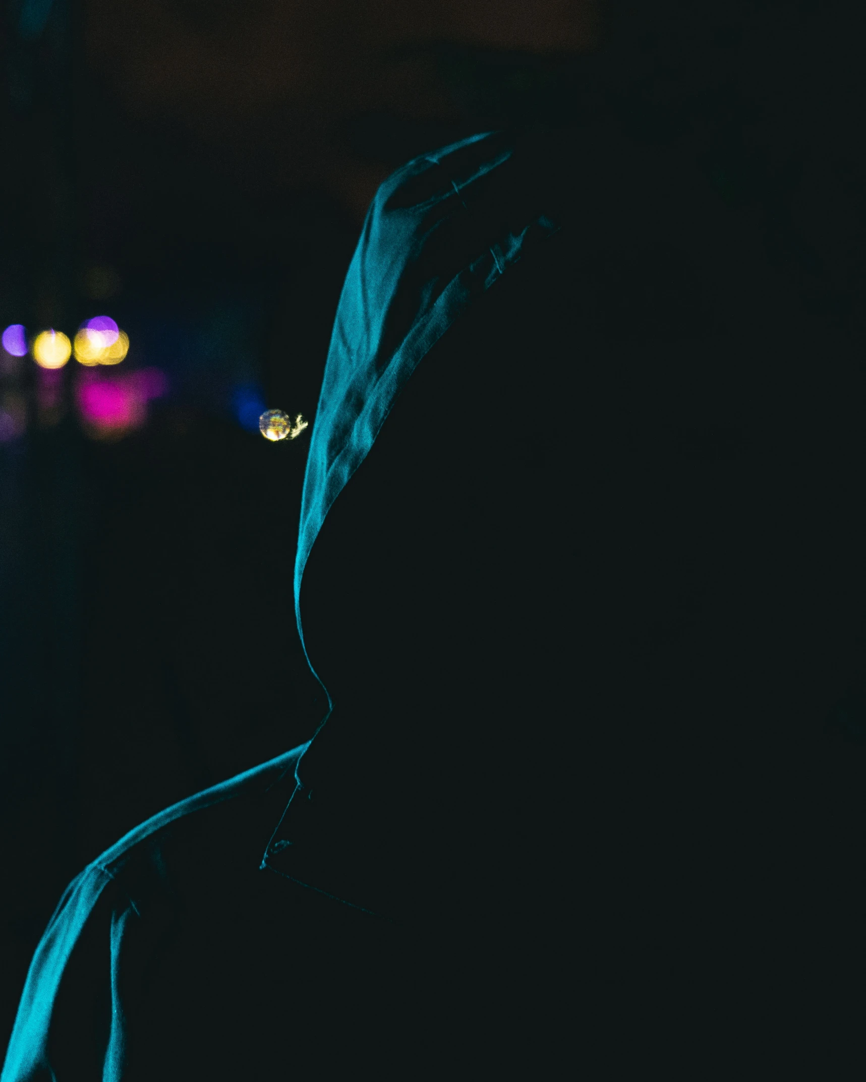 a silhouetted person in a dark room with buildings in the background