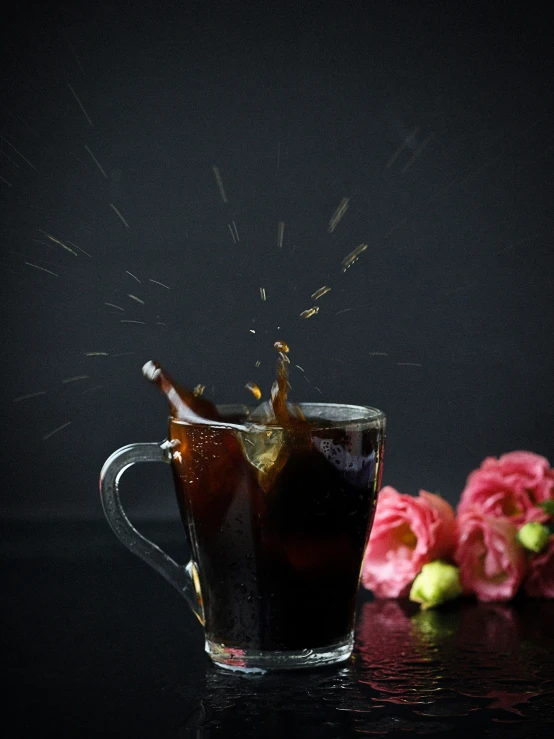 a glass mug full of tea next to some pink flowers