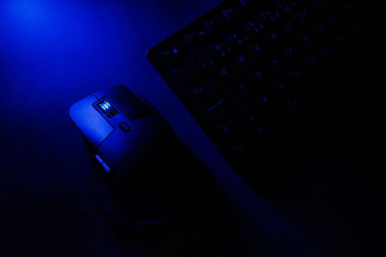 a computer mouse and keyboard illuminated by bright blue lights