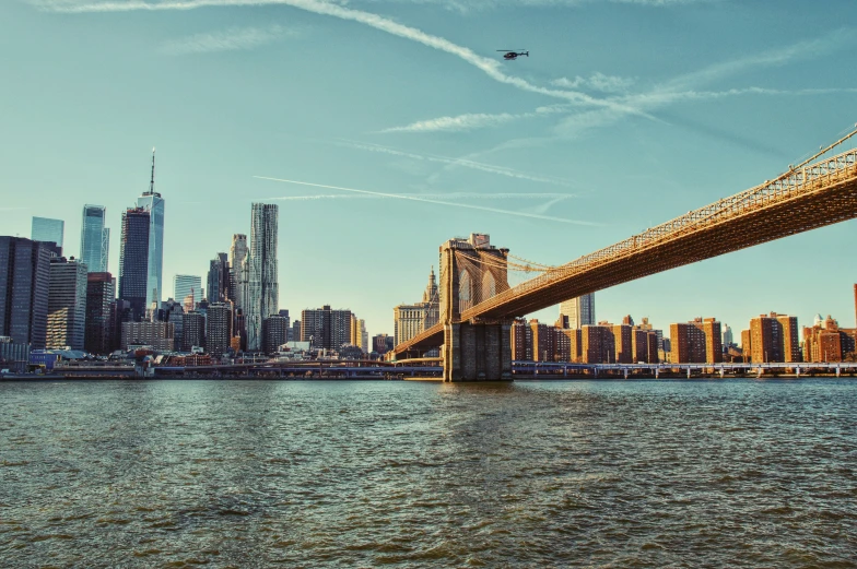 an airplane flying over the city in front of a bridge