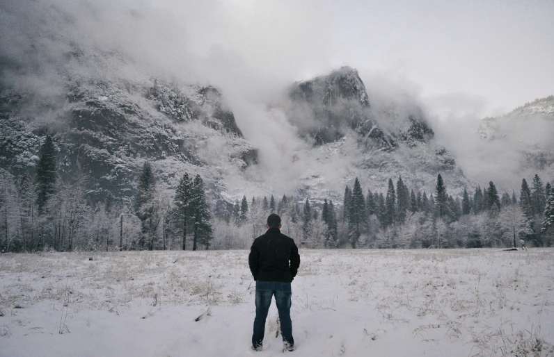 a man standing in a snowy field looking off to the side