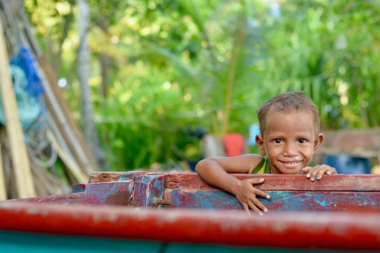 a smiling boy laying on top of a barrel of water