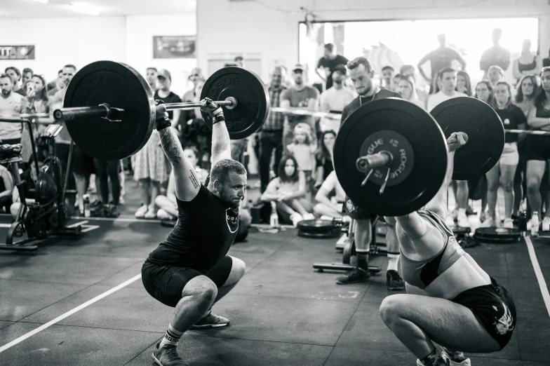 two women holding barbells in a gym