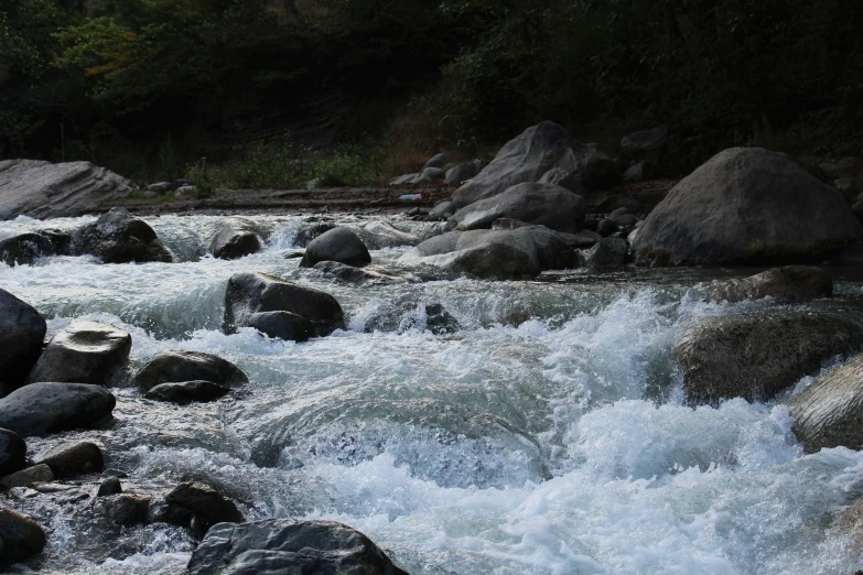 the water of a fast moving river flows between large rocks